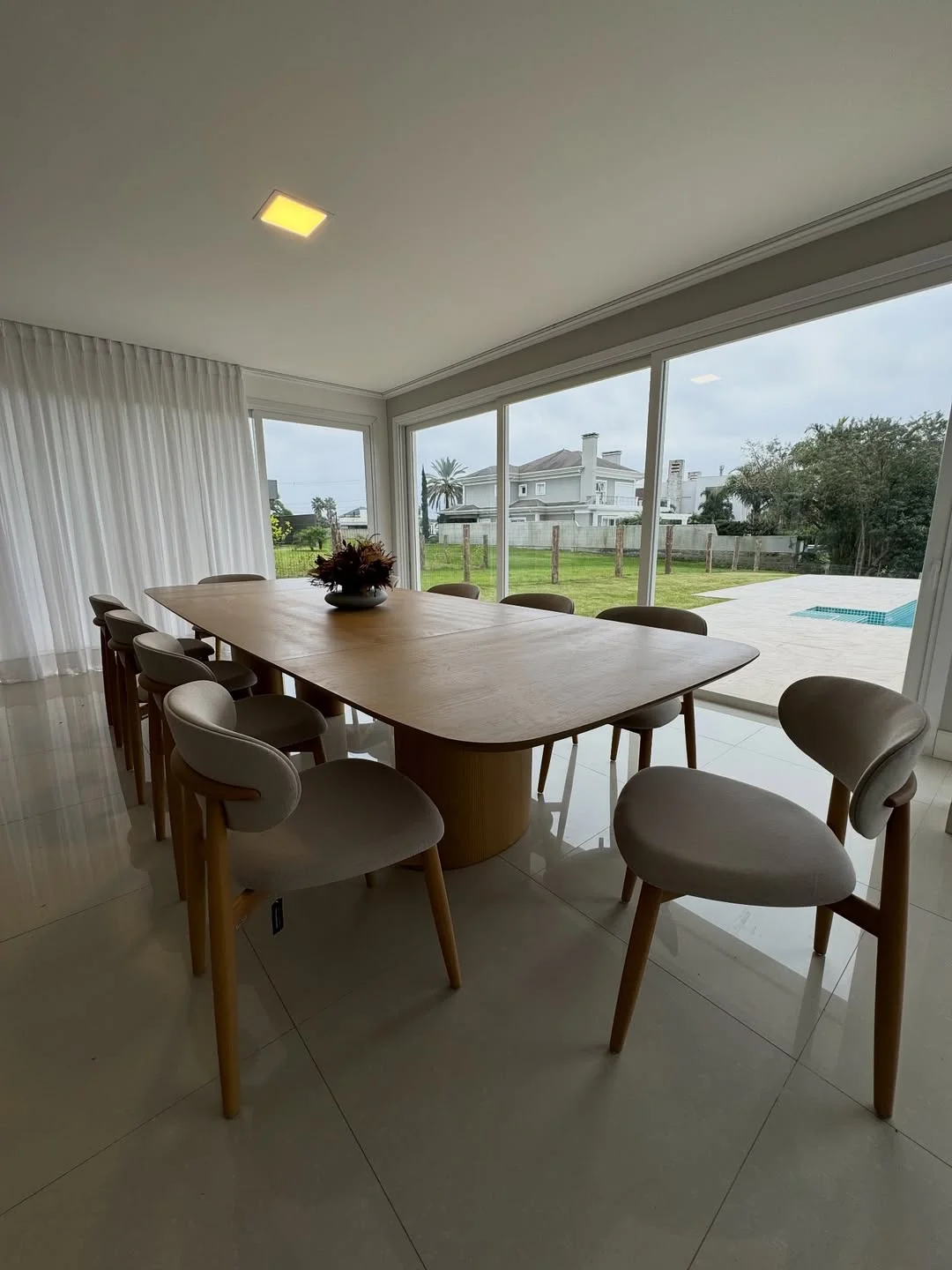 Sala de jantar com mesa de madeira e cadeiras estofadas, com vista para o jardim
