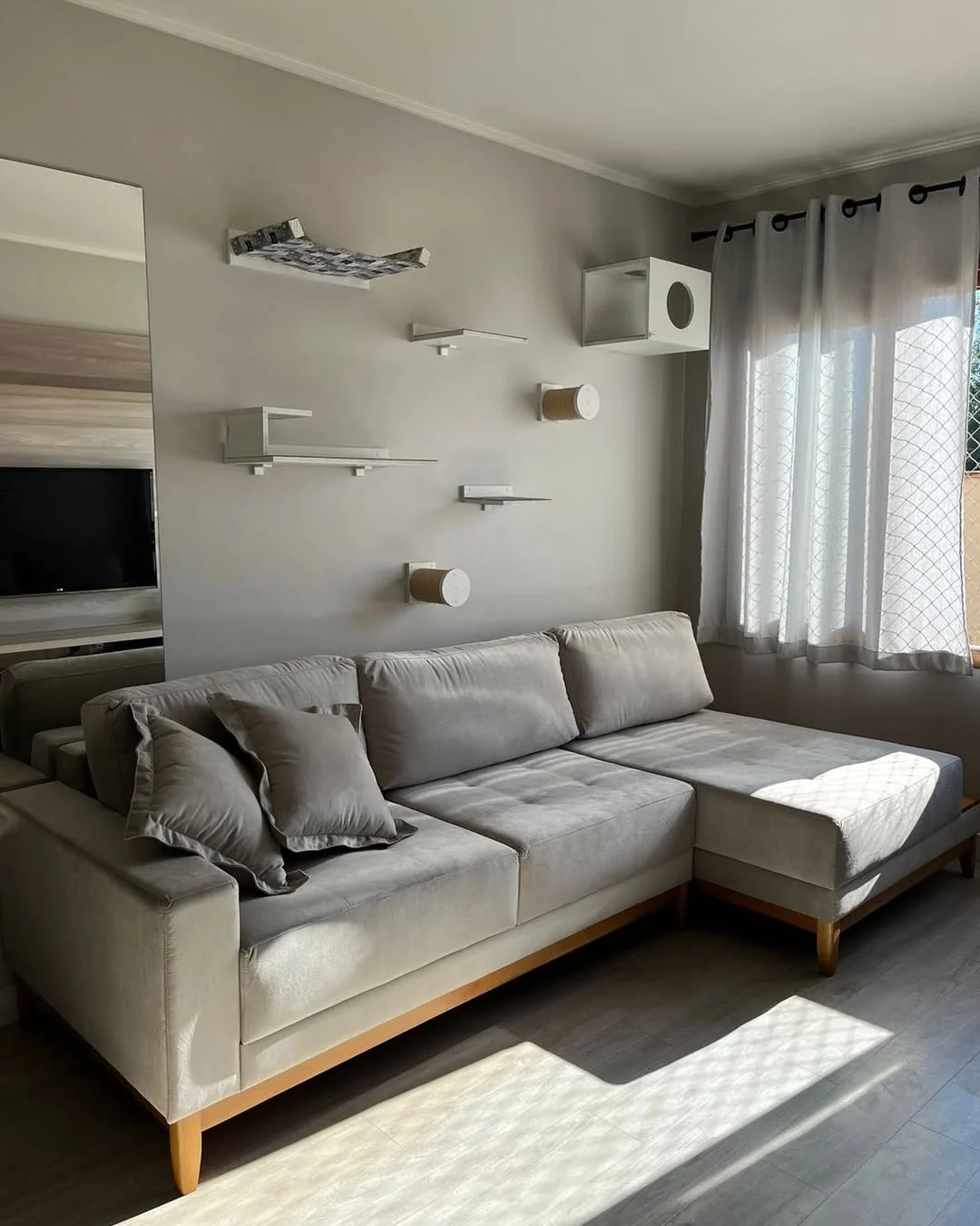 Sofá cinza com chaise em sala iluminada